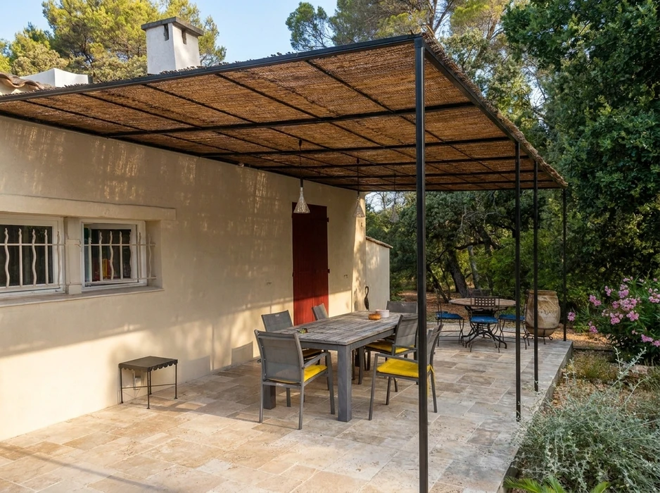 Terrasse extérieure couverte d'une pergola à structure métallique noire avec toiture en canisse