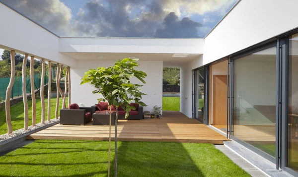 Terrasse moderne couverte avec mobilier de jardin en résine tressée rouge sur plancher bois