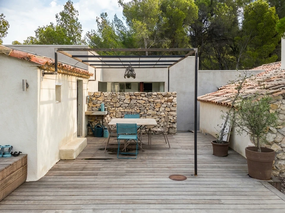 Terrasse extérieure avec pergola métallique à toit polycarbonate, table et chaises Fermob turquoise sur deck en bois composite