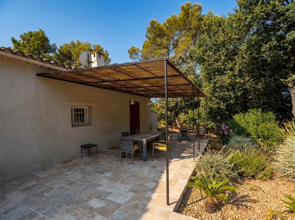 Terrasse couverte d'une villa méditerranéenne, vue sur piscine et jardin arboré